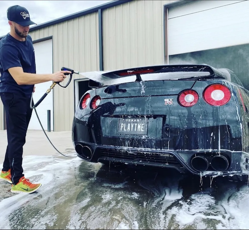 Rinsing foam from the rear of a black Nissan GT-R during a wash and seal