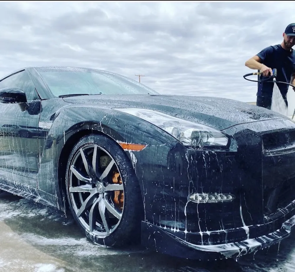 Landon foam-washing the front of a black Nissan GT-R